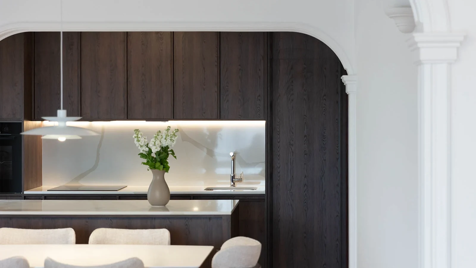 Dining area and dark oak kitchen framed by an original plaster arch in BP77 Apartment