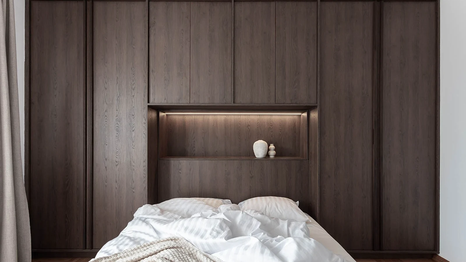 Integrated bed niche framed by full-height dark oak wardrobes in BP77 Apartment