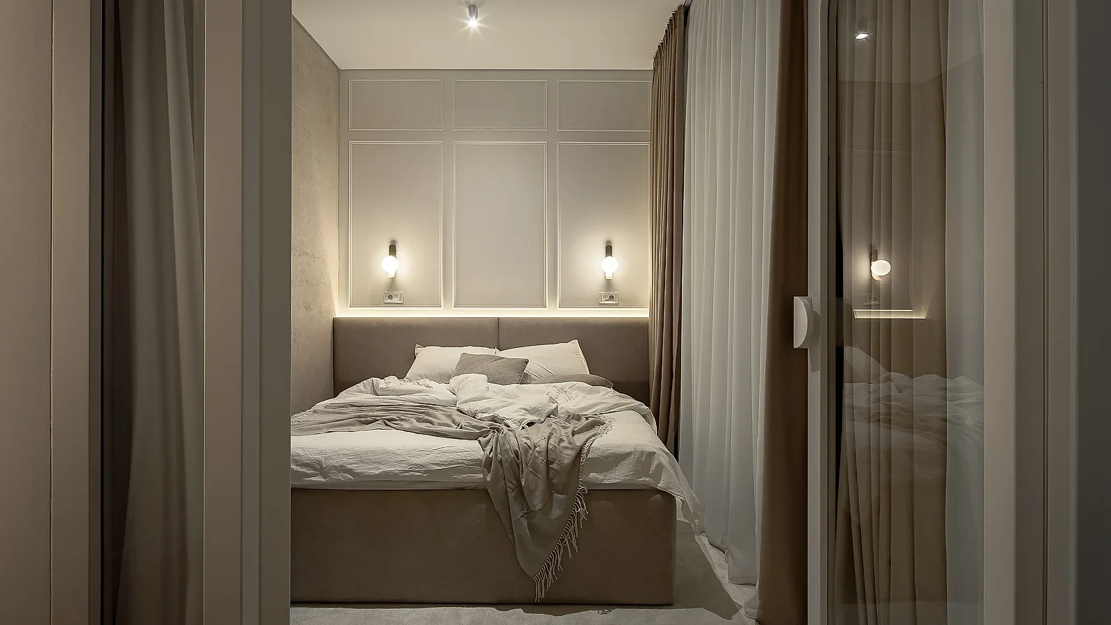 KMR bedroom framed by layered curtains with soft wall lighting and neutral textiles