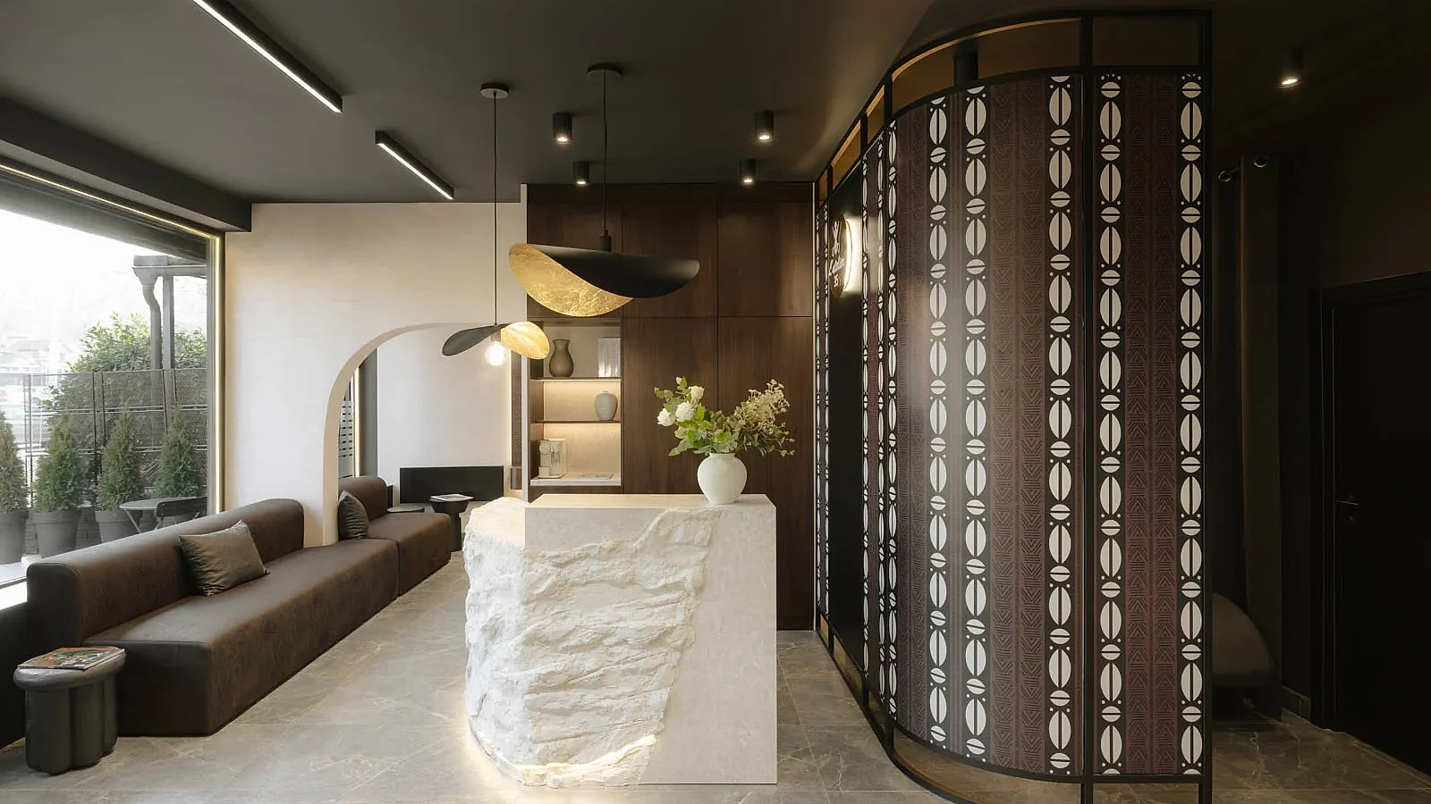 Waiting lounge, stone reception desk and patterned screen inside L'Atelier 35 hair salon