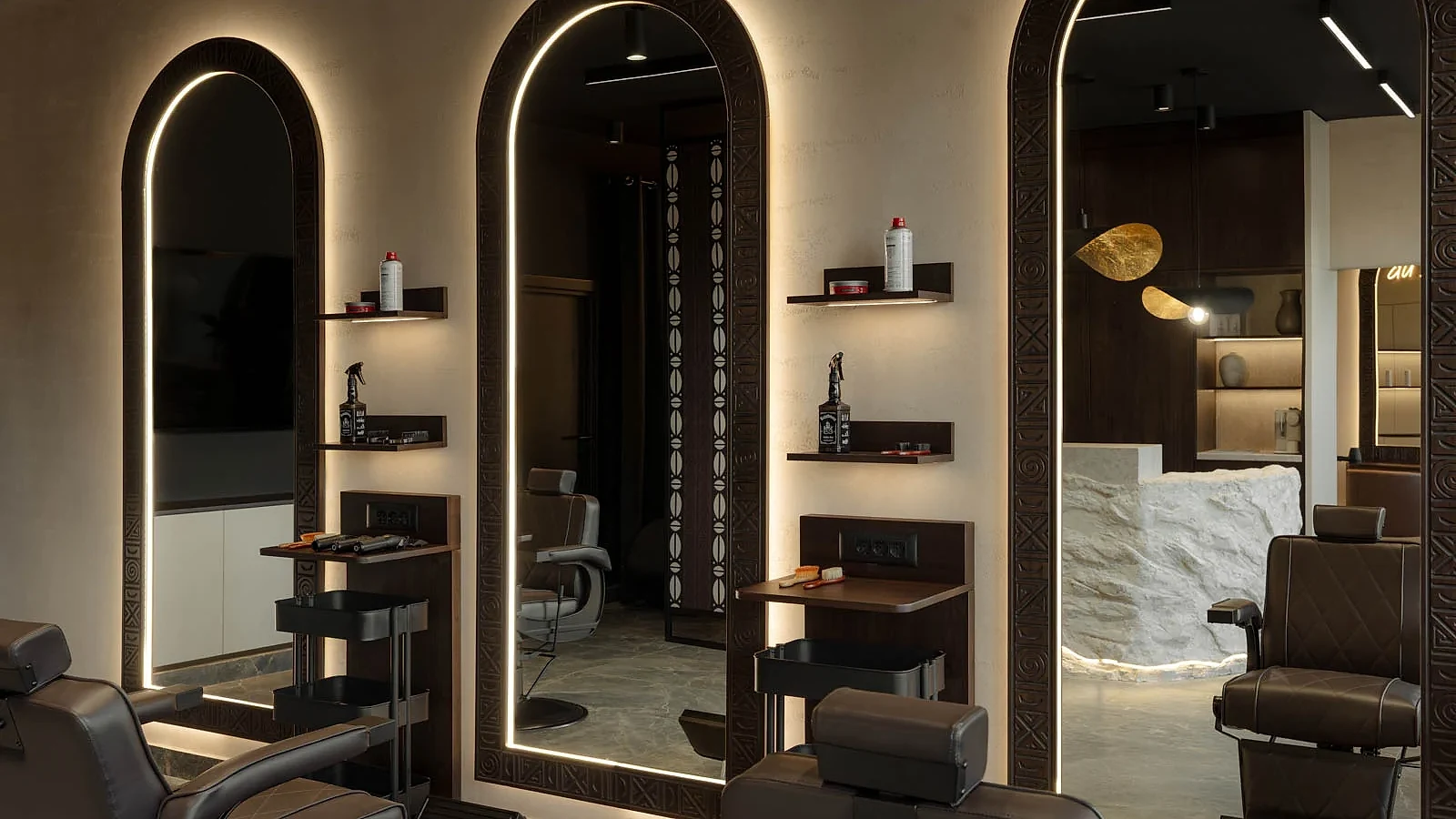 Barber chairs facing illuminated arched mirrors in the dark wood interior of L'Atelier 35