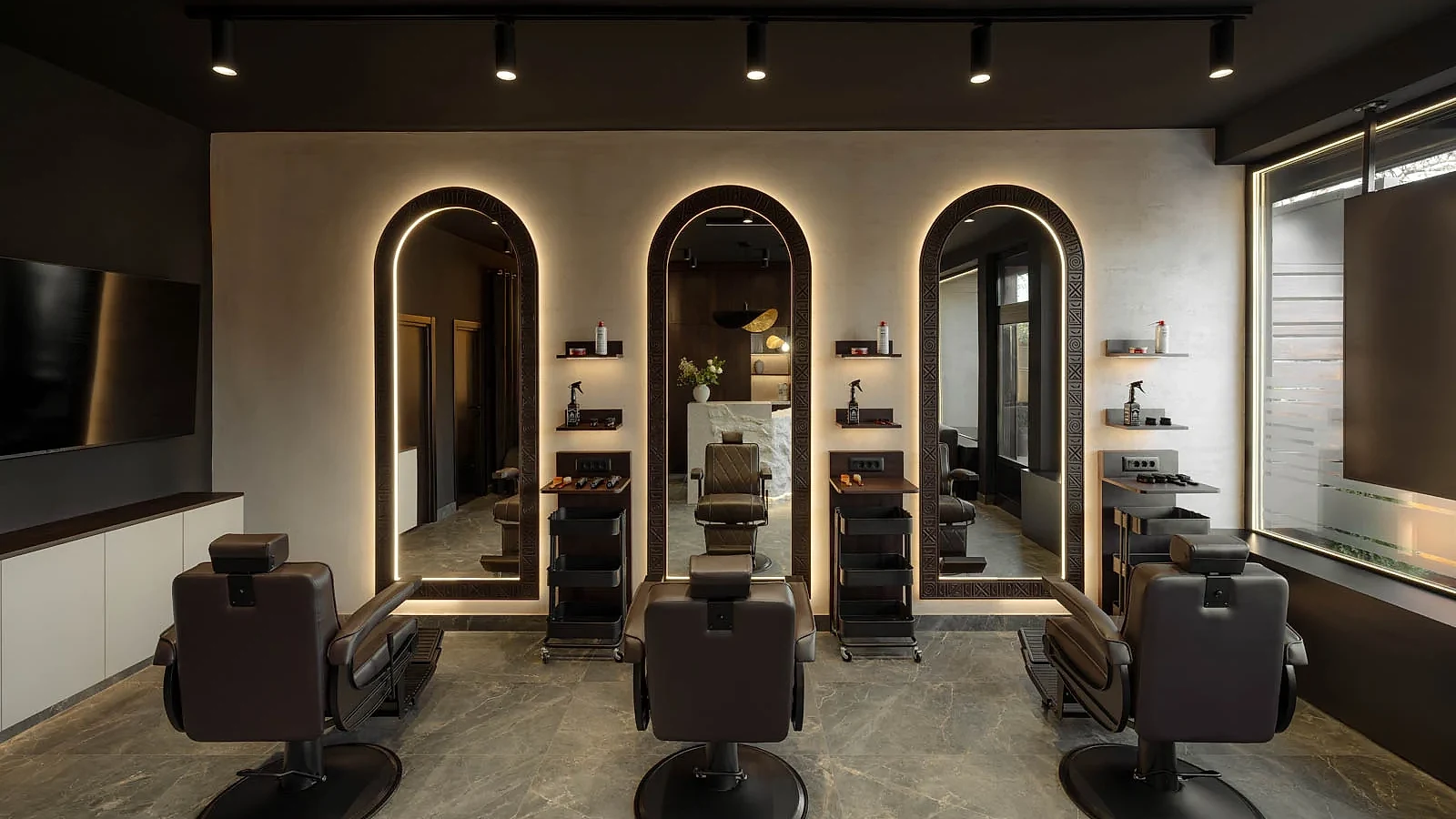 Three barber chairs and illuminated arched mirrors in the barbering area at L'Atelier 35
