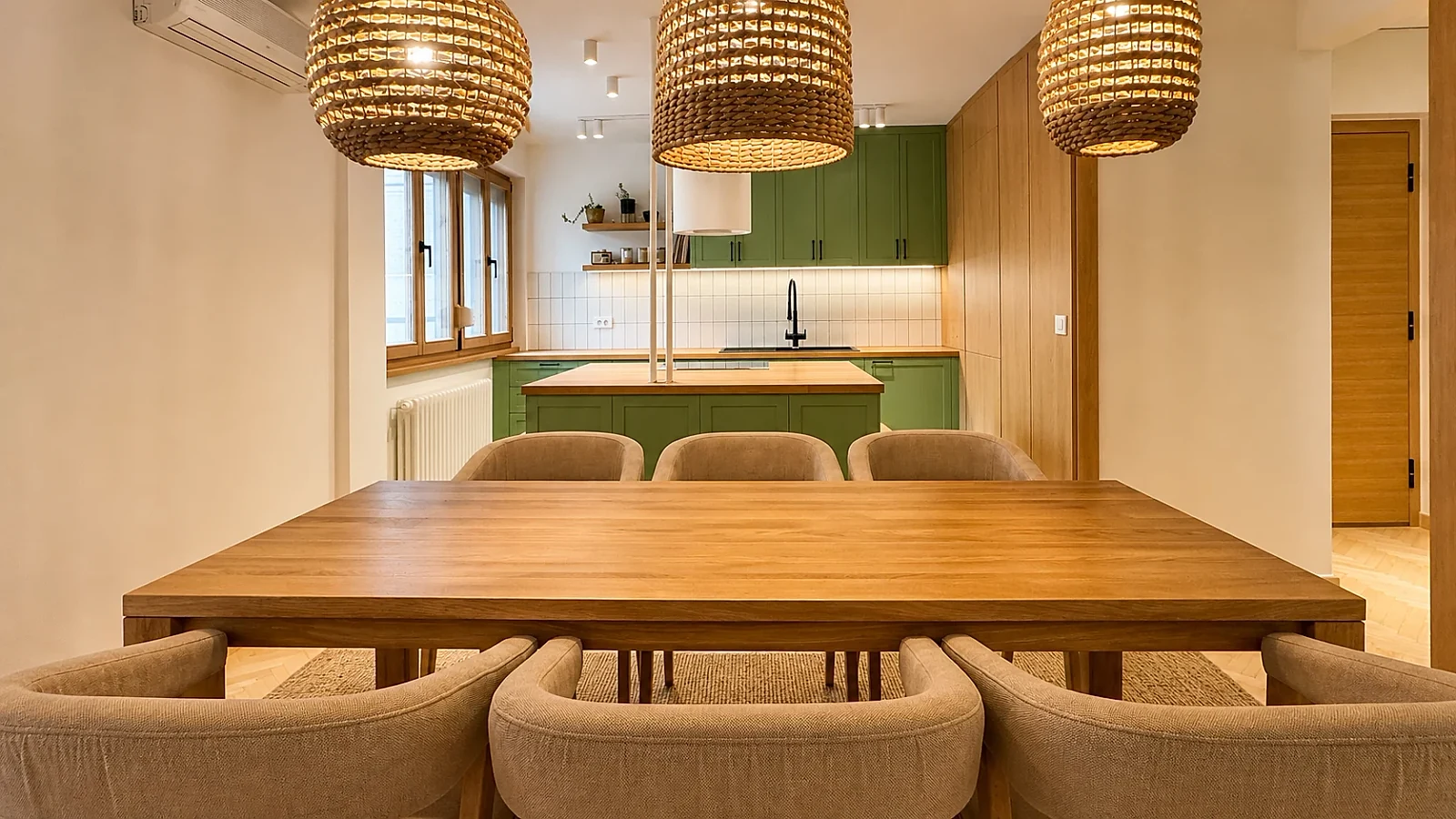 MC33 Apartment view across the dining table toward the green kitchen island and natural timber joinery
