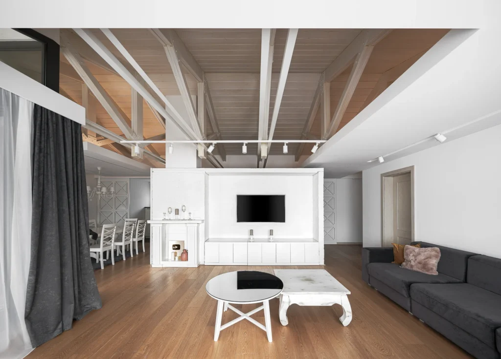 S27 living room with dark sectional seating, white media wall and exposed timber ceiling