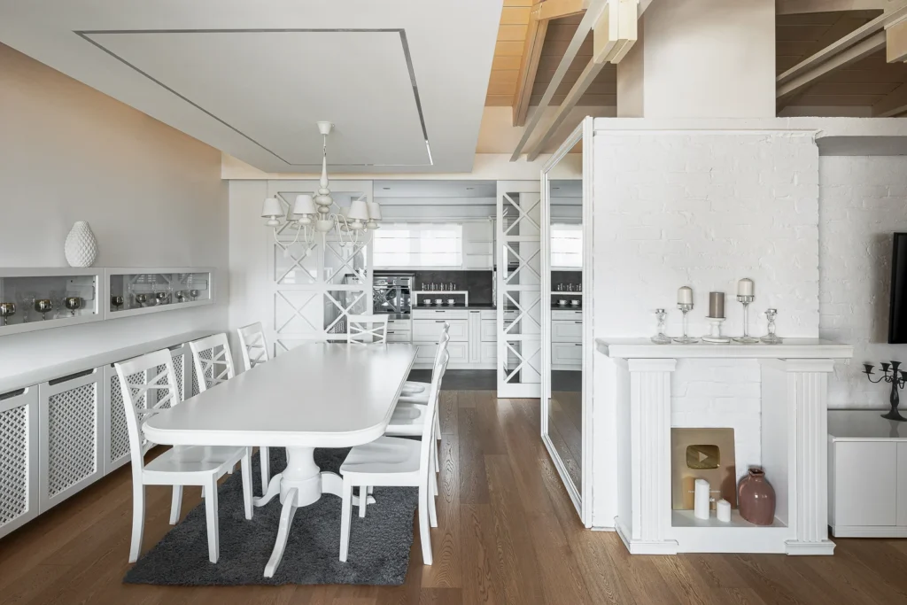S27 dining area with a white table, chandelier and custom shelving around the fireplace