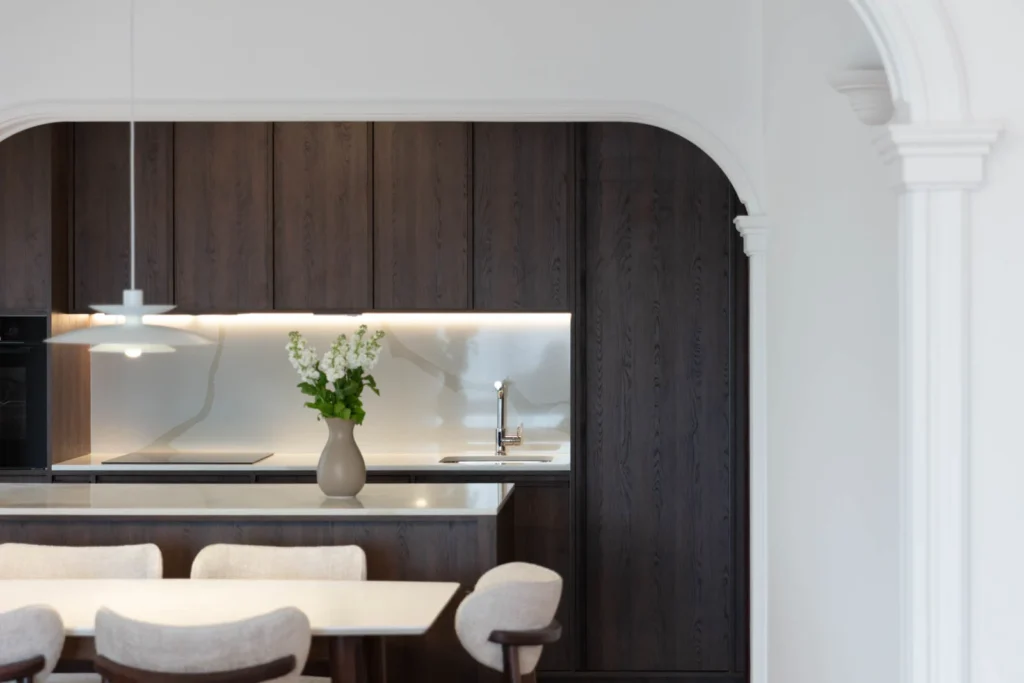 Dining area and dark oak kitchen framed by an original plaster arch in BP77 Apartment