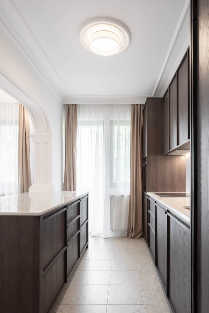 Dark oak galley kitchen with stone worktops and daylight in BP77 Apartment