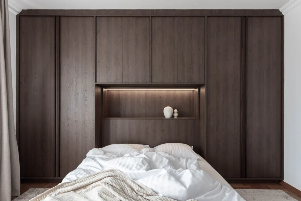 Integrated bed niche framed by full-height dark oak wardrobes in BP77 Apartment