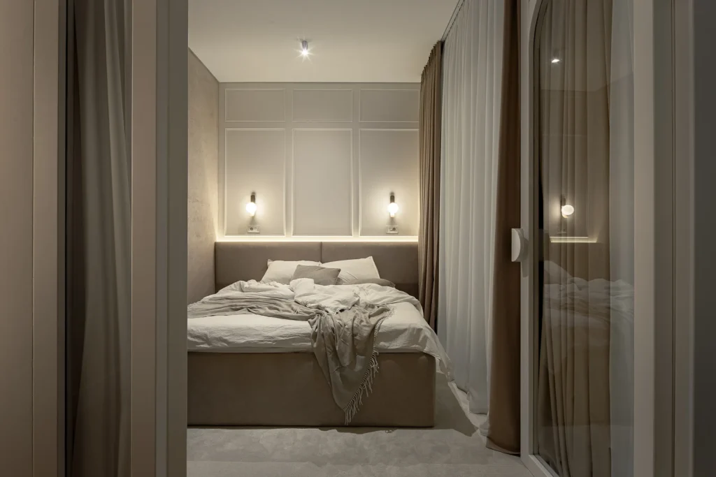KMR bedroom framed by layered curtains with soft wall lighting and neutral textiles
