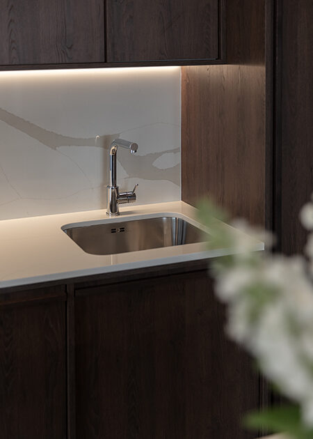 Custom dark wood kitchen with an illuminated stone backsplash