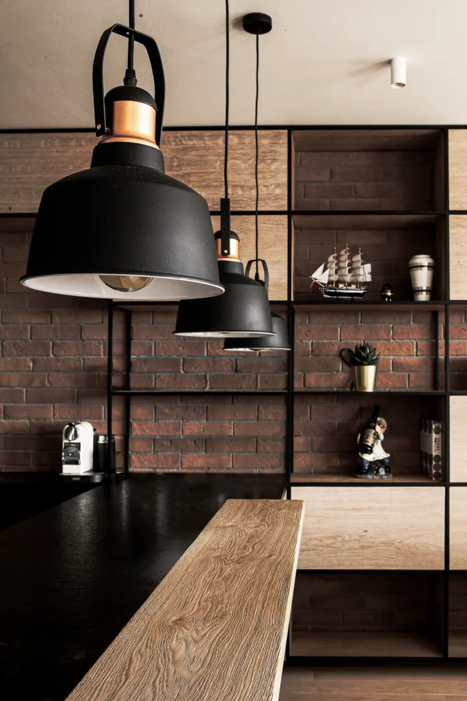 Black pendant lights and open timber shelving in the A75 Apartment kitchen