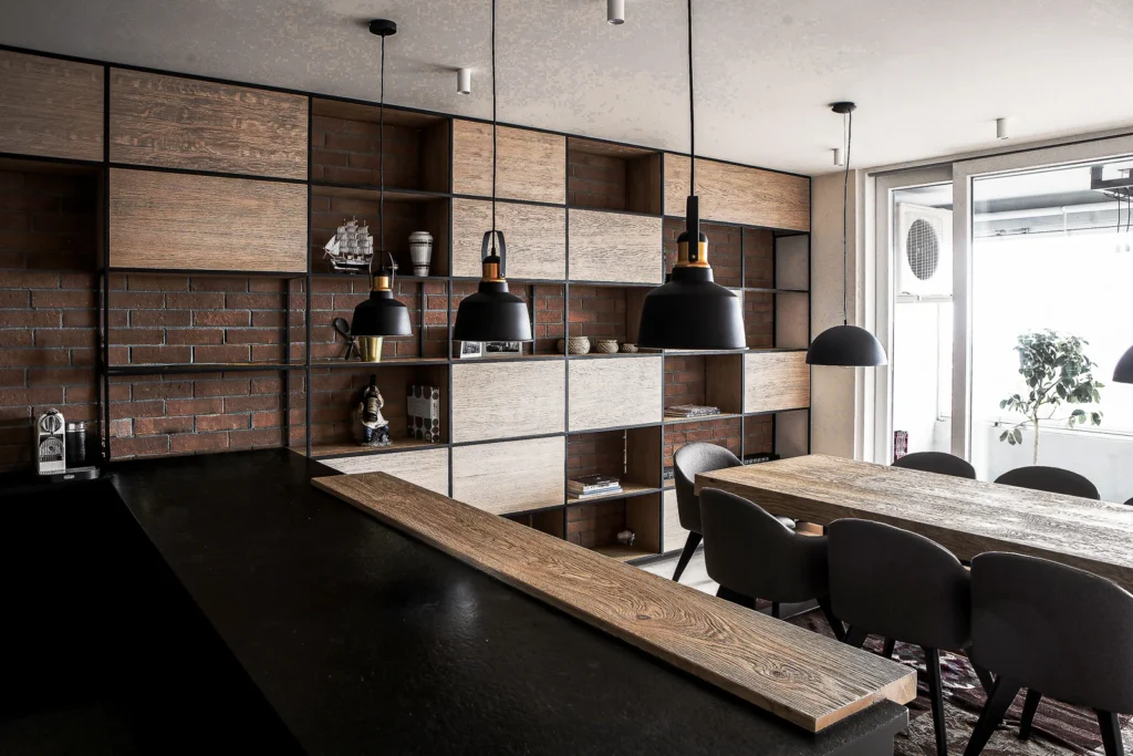 A75 Apartment open-plan kitchen and dining area with black cabinetry, exposed brick and warm wood