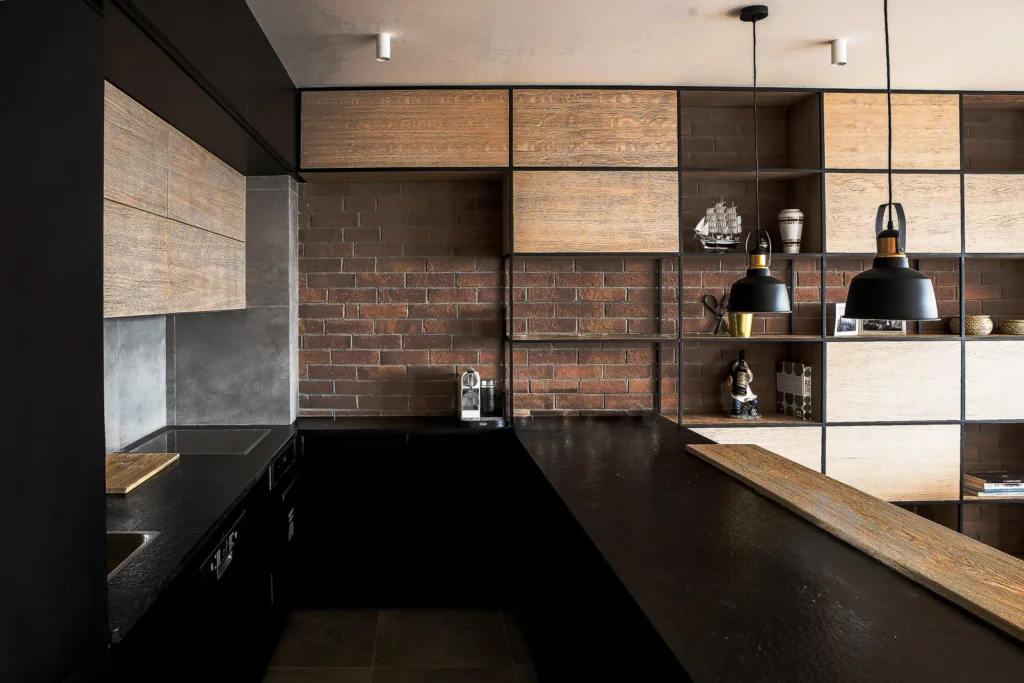 A75 Apartment kitchen combining black cabinetry, exposed brick and warm timber