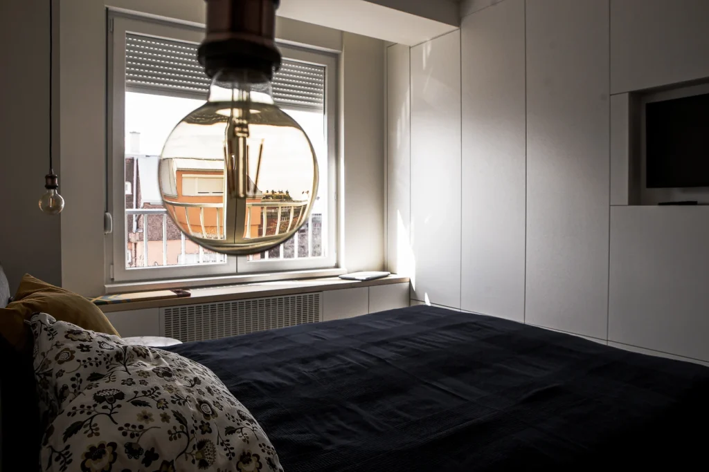 A75 Apartment bedroom with integrated white wardrobes and a city-view window