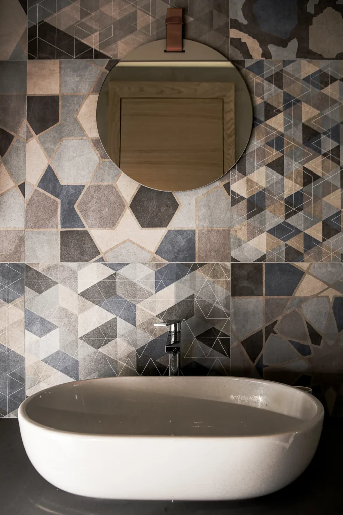 Geometric tile wall, round mirror and freestanding basin in the A75 Apartment bathroom