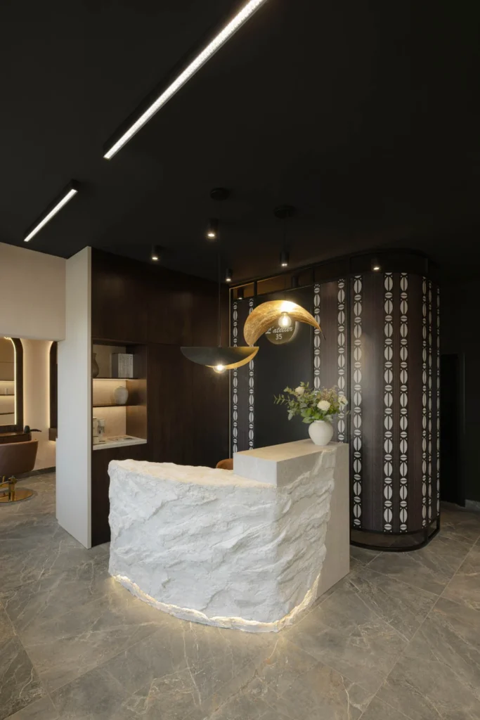 L'Atelier 35 hair salon reception with a textured stone desk and curved patterned screen