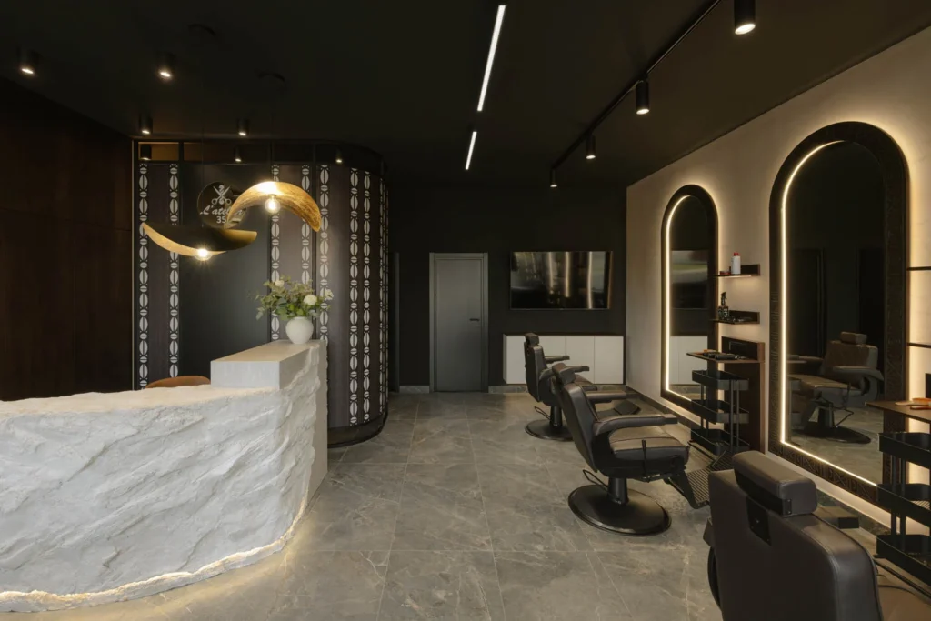 L'Atelier 35 hair salon interior with the stone reception desk and illuminated barber stations