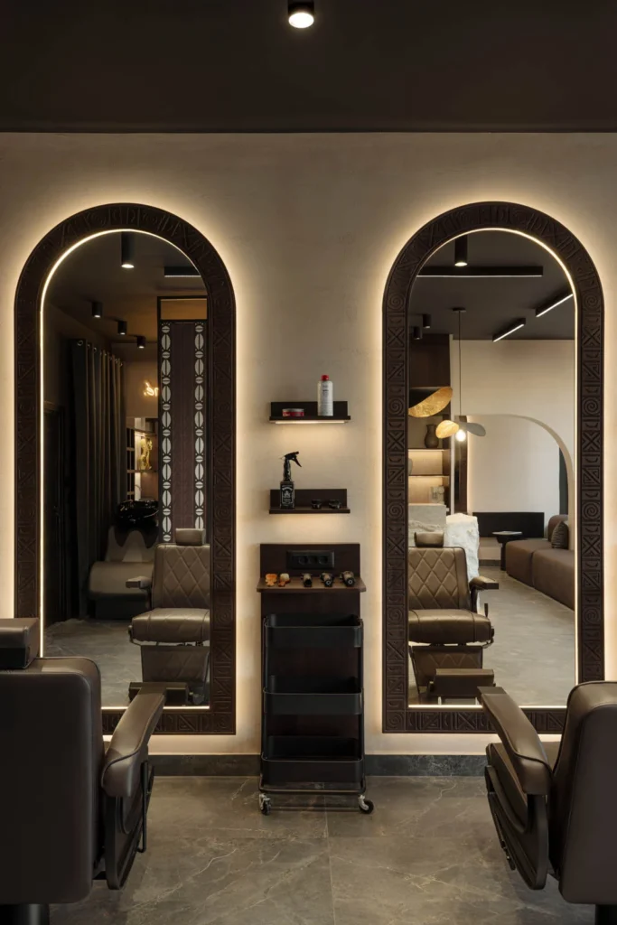 Pair of illuminated arched barber mirrors with custom carved details at L'Atelier 35