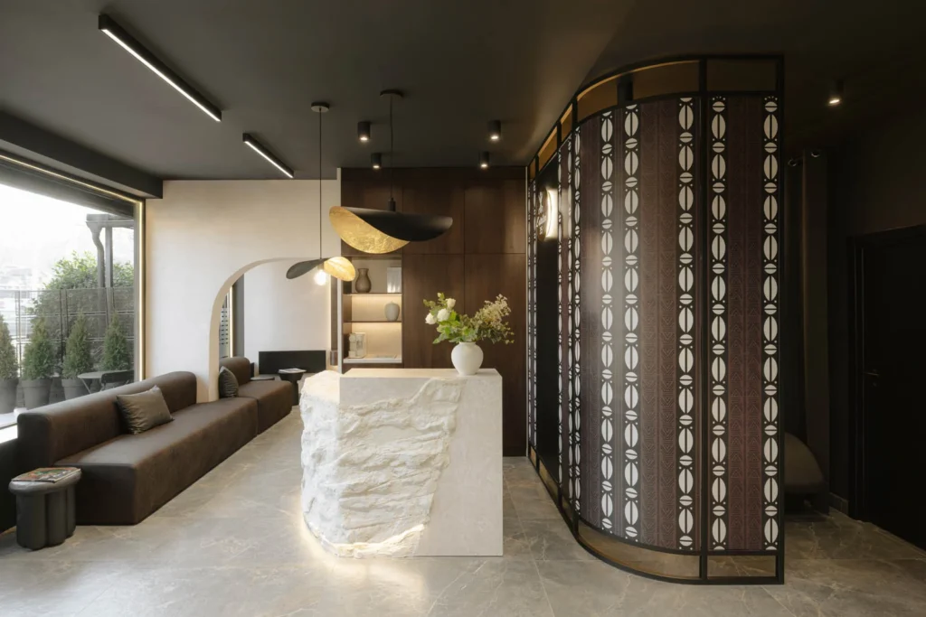 Waiting lounge, stone reception desk and patterned screen inside L'Atelier 35 hair salon