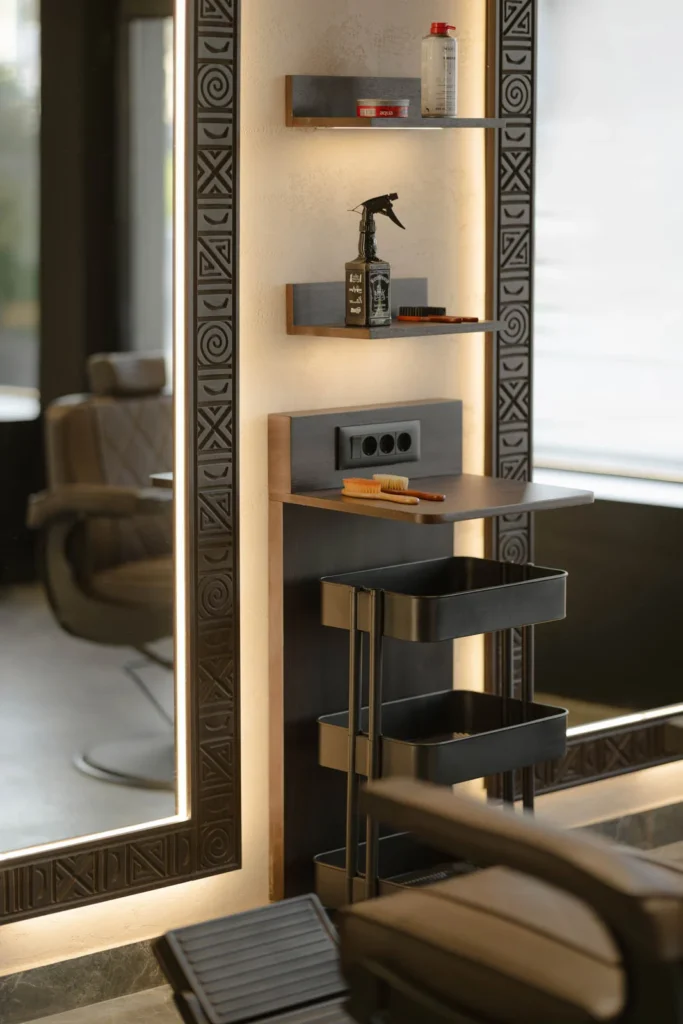 Close view of an illuminated salon mirror and dark wood product shelves at L'Atelier 35