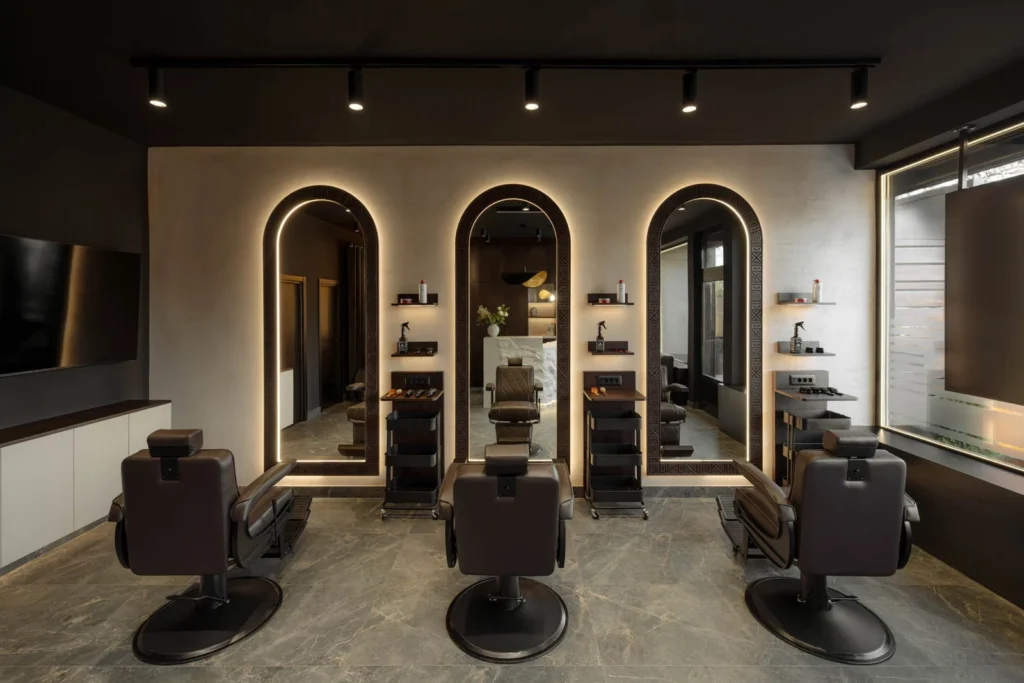 Three barber chairs and illuminated arched mirrors in the barbering area at L'Atelier 35