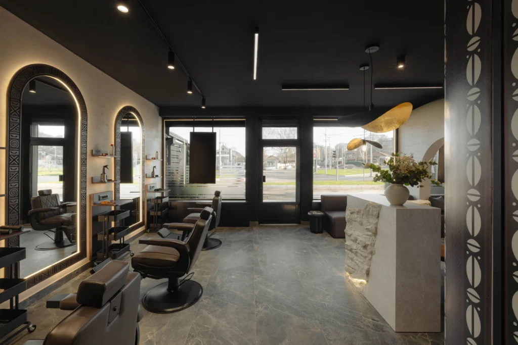 View through the L'Atelier 35 salon from the barber stations toward the glazed entrance