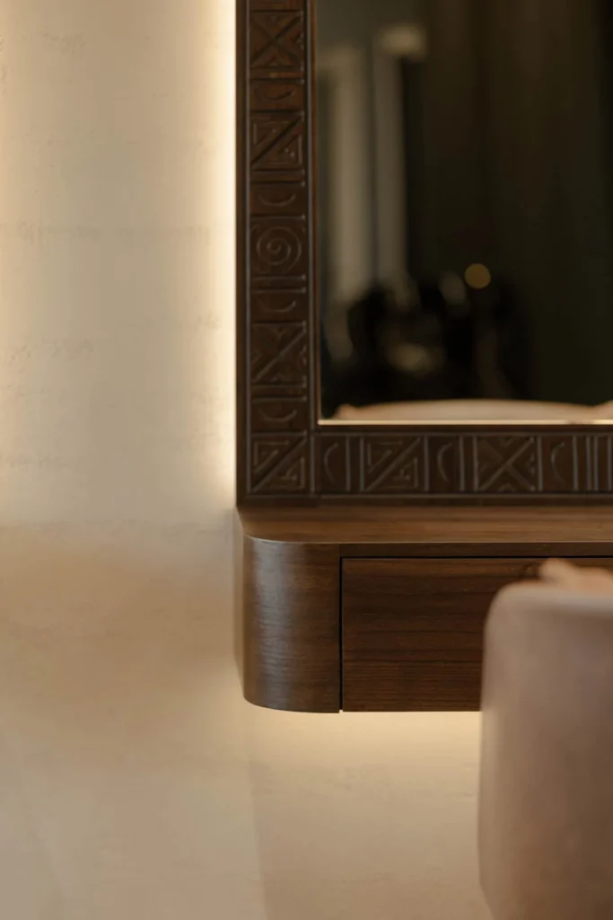 Close view of a carved dark wood mirror frame and brown leather seating at L'Atelier 35