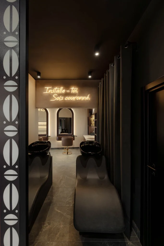View into the barbering area through the curved screen with African-inspired patterns