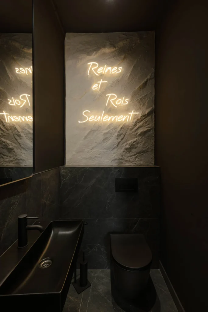 Dark hair washing area with reclining basins, stone panel and French neon lettering