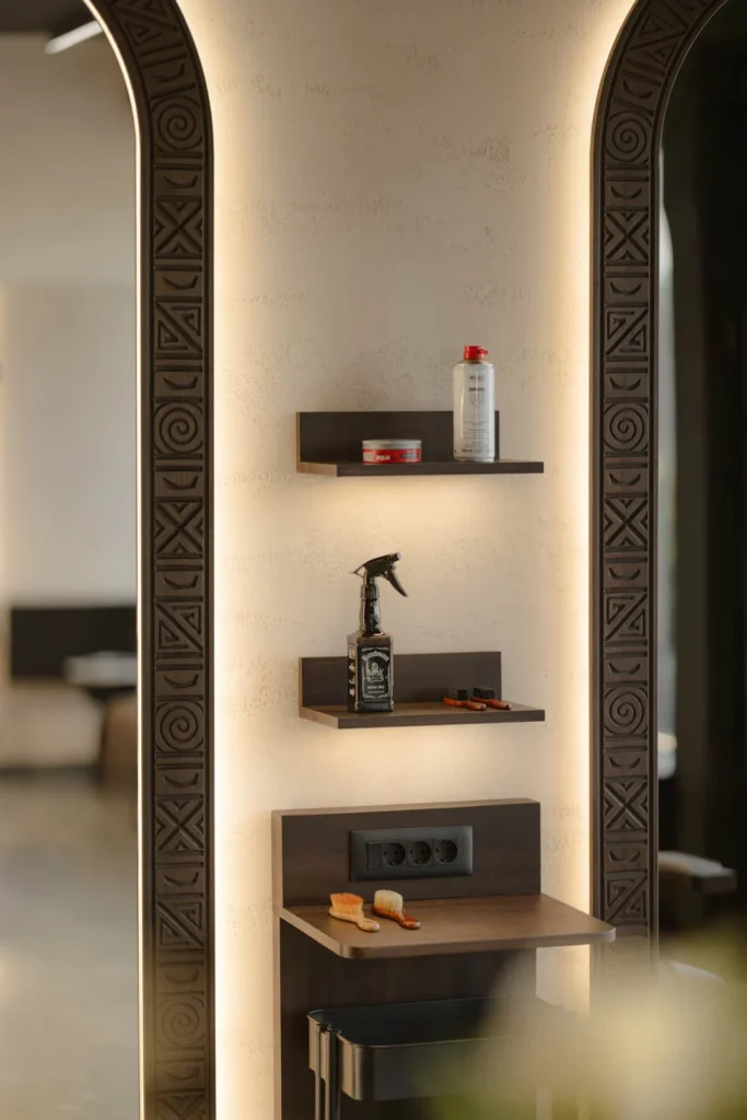 Close view of an arched illuminated mirror and product display shelves at L'Atelier 35