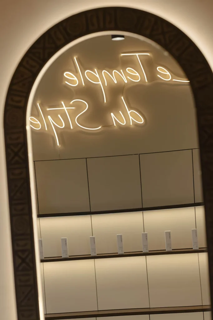 Arched salon mirror reflecting French neon lettering in the L'Atelier 35 interior