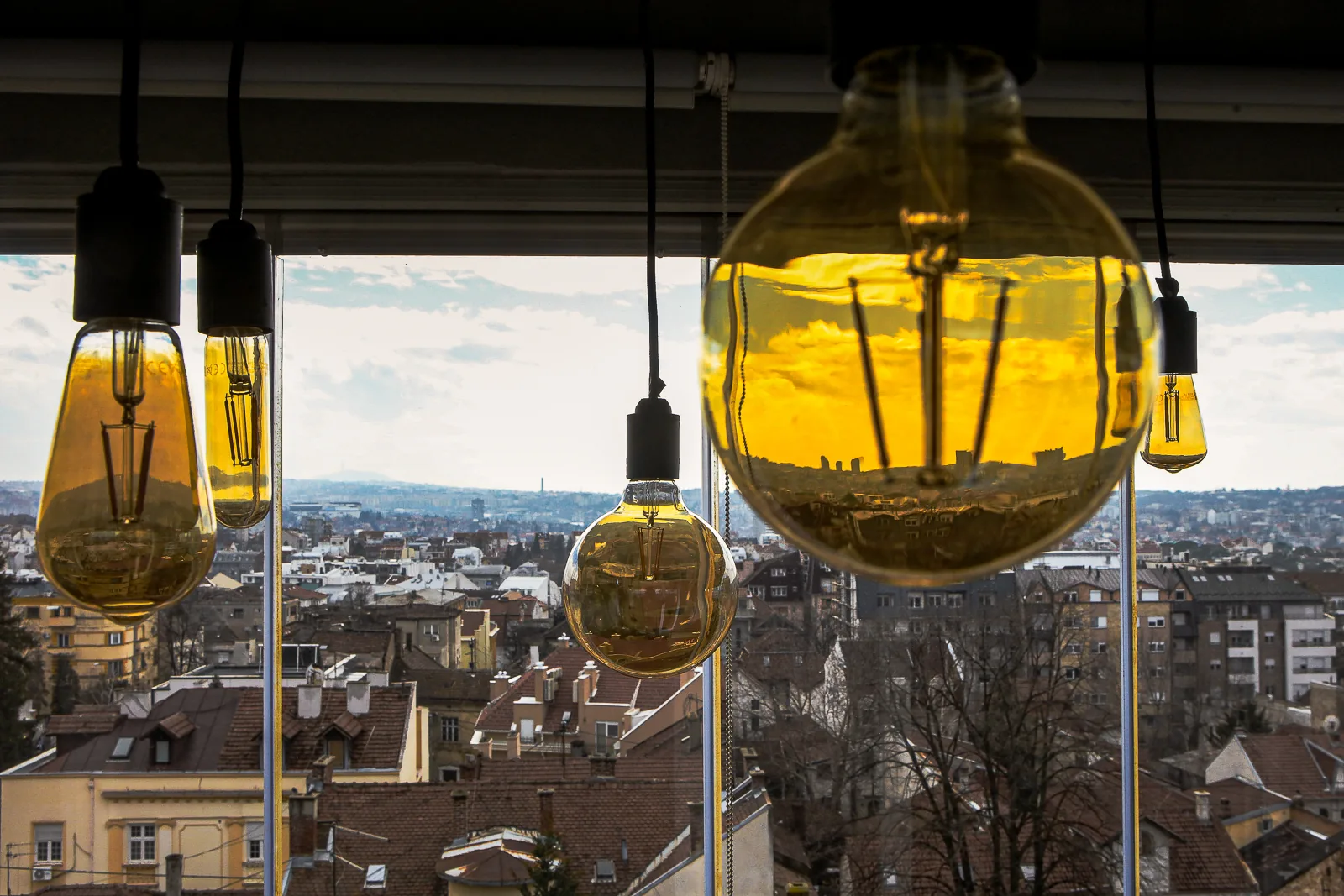 Amber glass pendant lights framing the Belgrade skyline from A75 Apartment