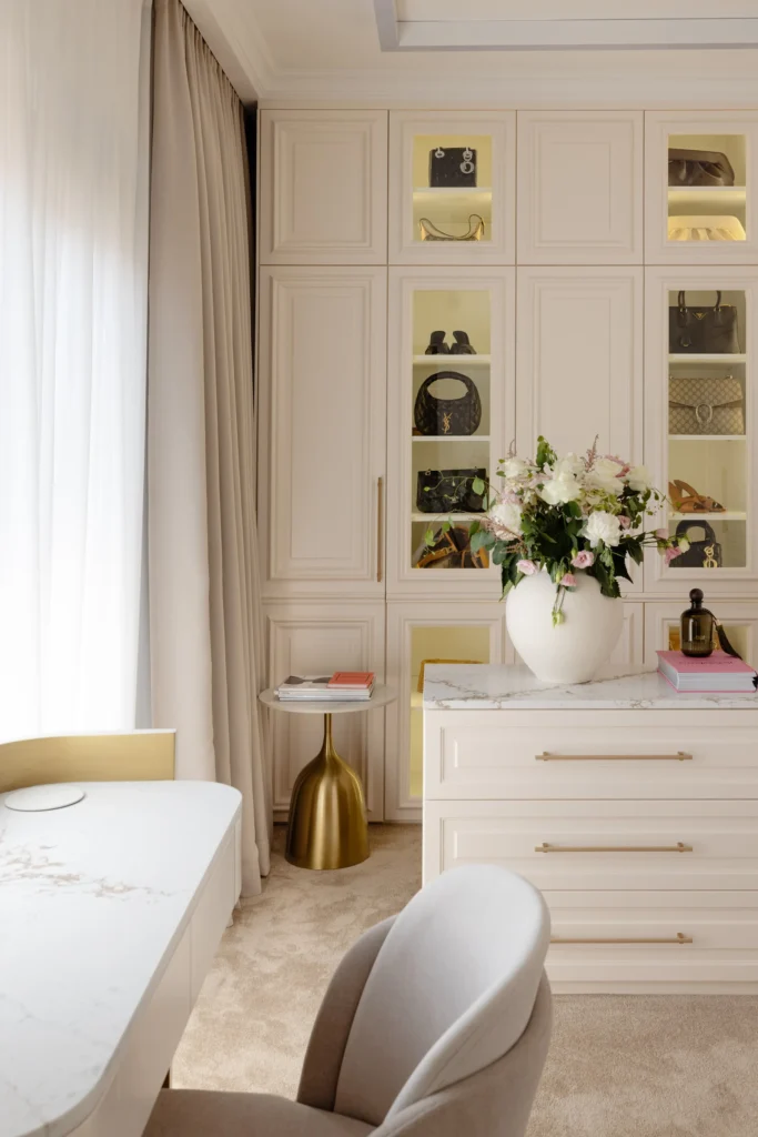 MBS Master Suite vanity and movable dresser with pale stone surfaces and brass details